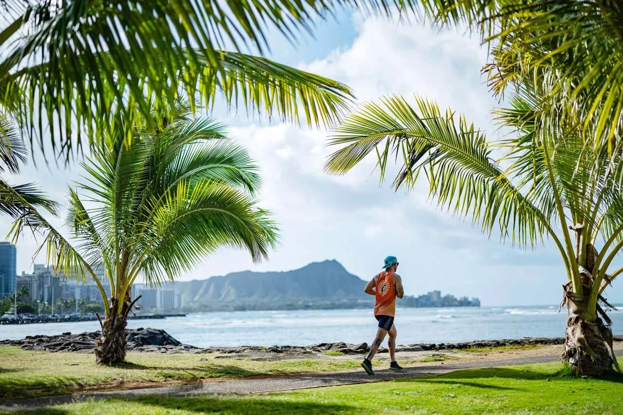 A participant running along the beach path with Diamond Head in the background
