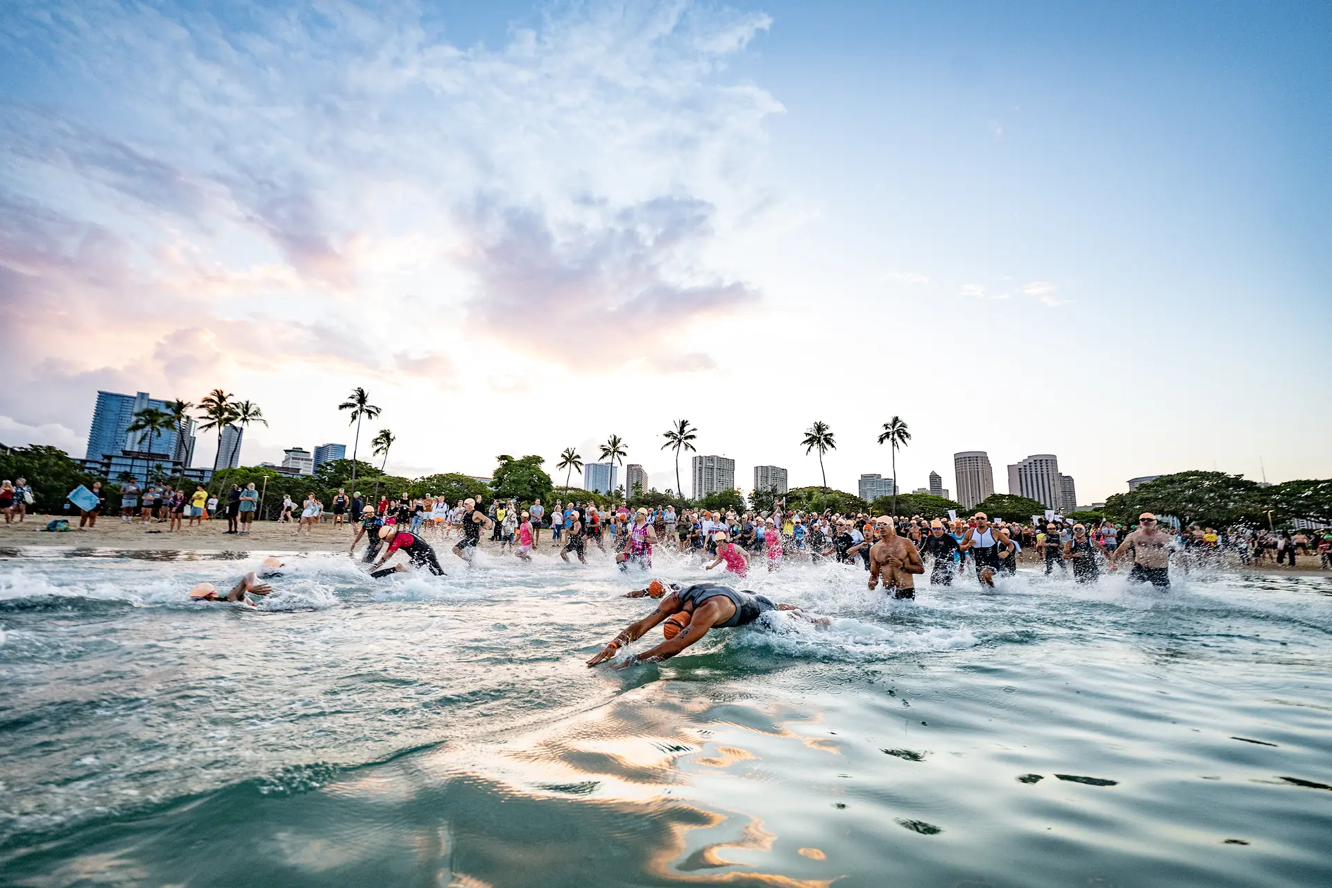 Athletes diving into the water at the swim start off Waikiki Beach